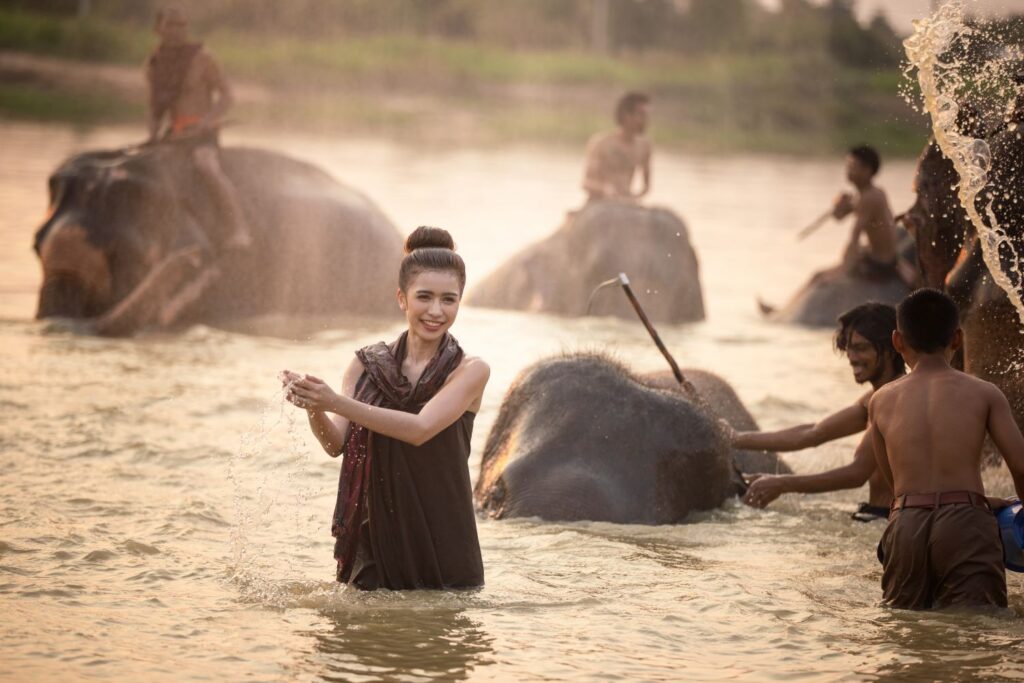 Portrait Of Smiling Woman Standing With Elephant In Thailand.