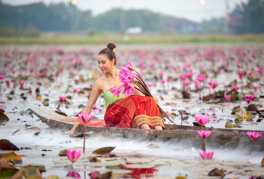 Young Asian Women In Traditional Dress In The Boat And Pink Lotus Flowers In The Pond.beautiful Girls In Traditional Costume.thai. Ayutthaya, Elegance.